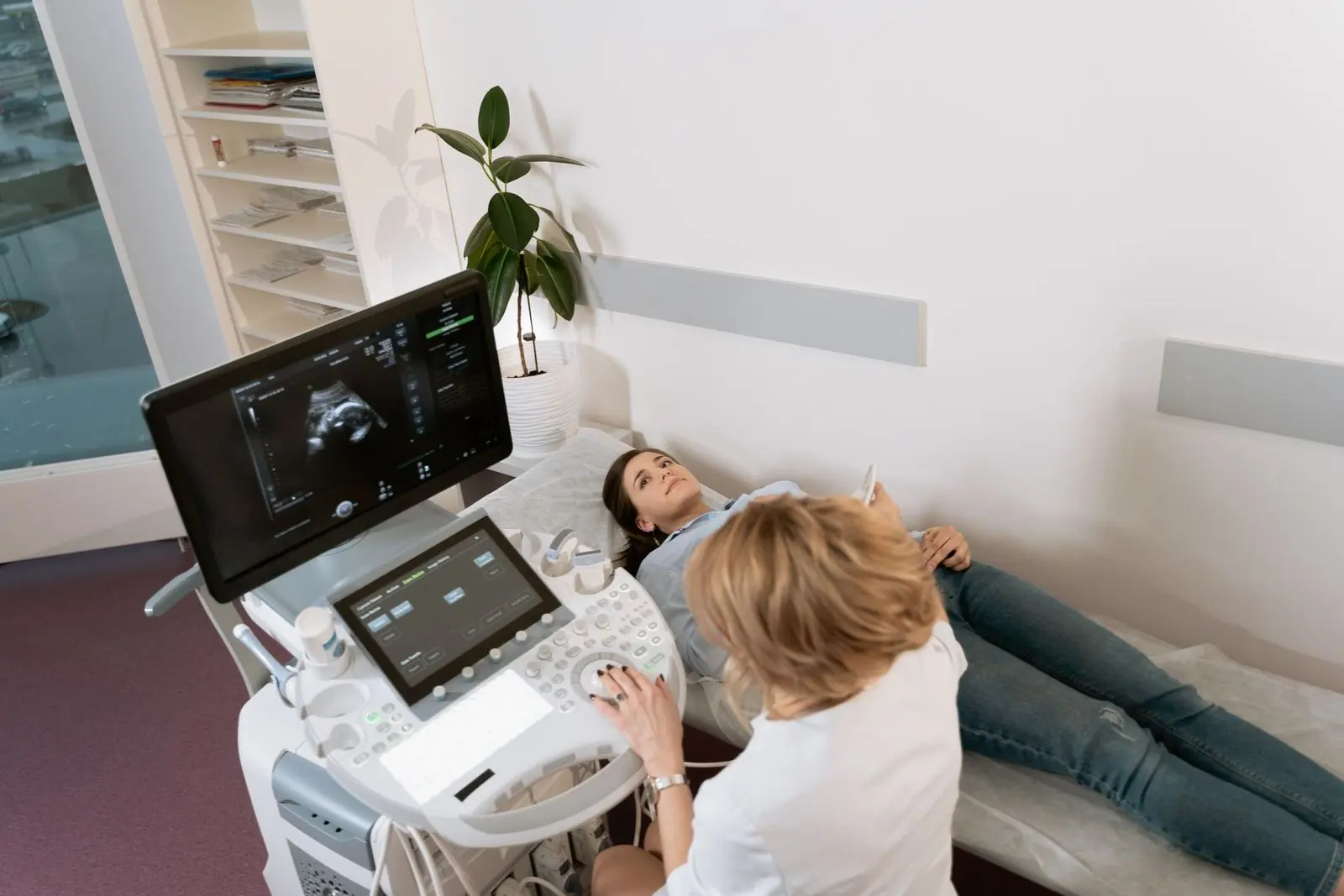 Sala de ultrasonido con equipo de ecografía y doctora trabajando